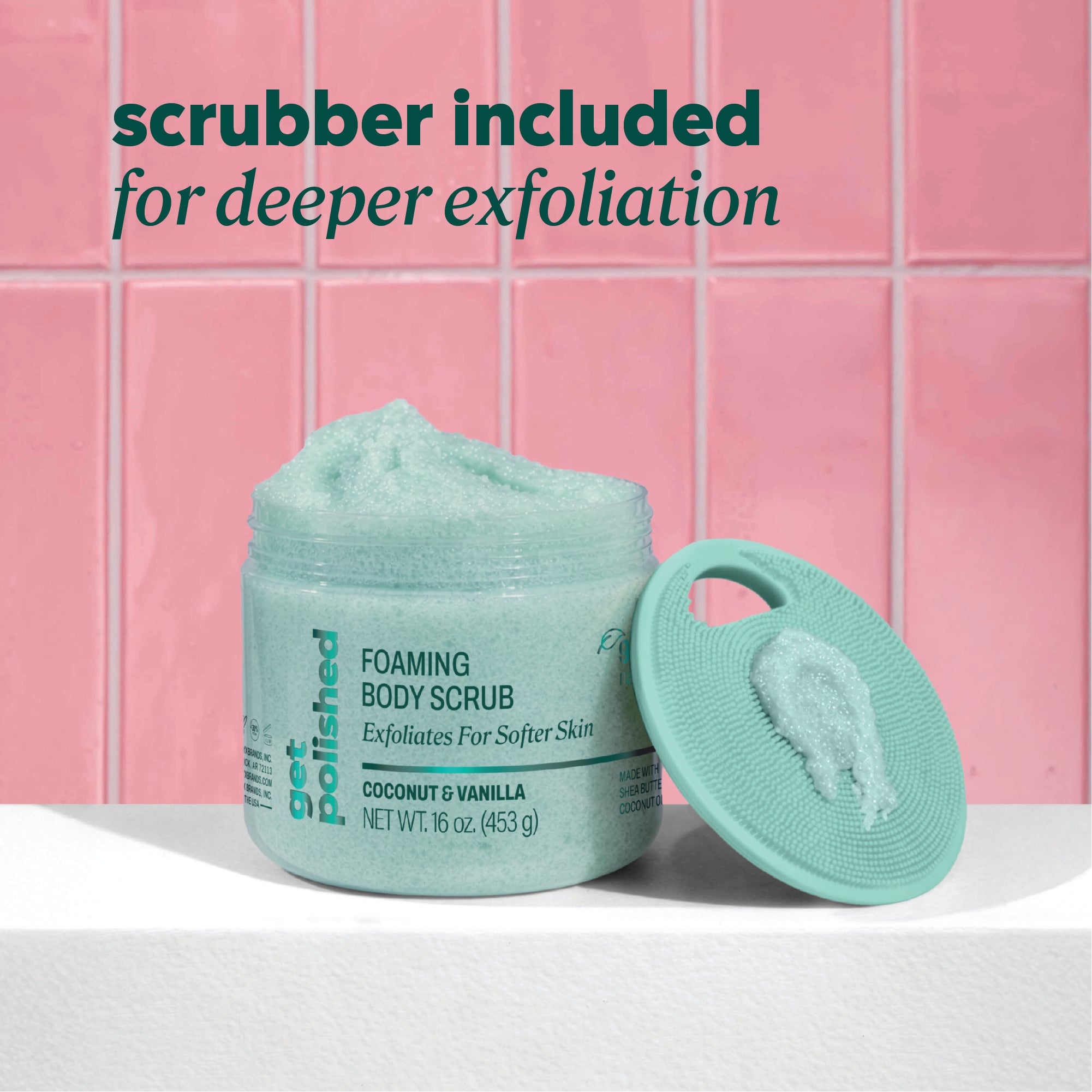 Open jar of Onyx Professional Foaming Body Scrub with scrubber lid leaning upright in front of pink tile. Text reads ‘scrubber included for deeper exfoliation.
