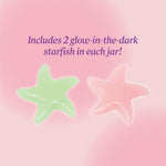 Two glow‑in‑the‑dark starfish—one green and one pink—displayed on a soft pink background with text reading ‘Includes 2 glow‑in‑the‑dark starfish in each jar.'